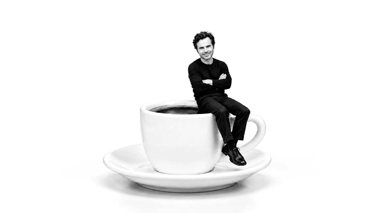 Paolo Bortolotti seduto sul bordo di una tazzina di caffè